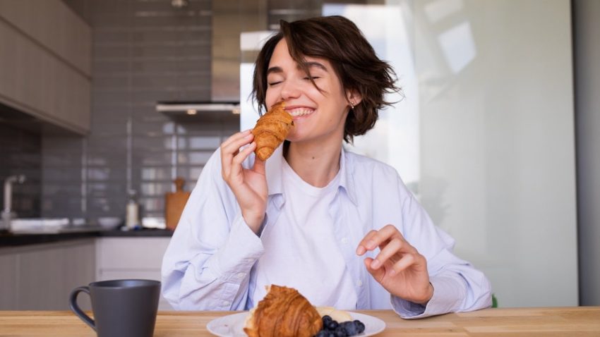 a woman sitting at a table eating a pastry